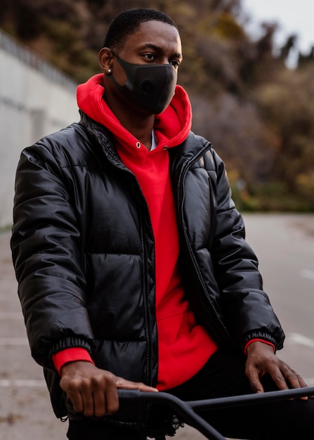 Free photo man wearing a mask and holding his bike