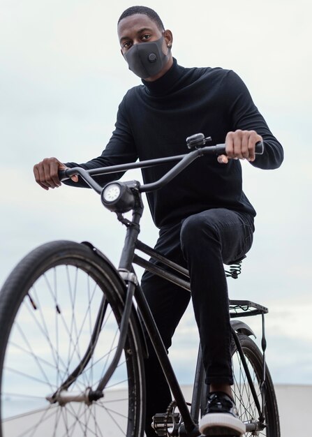 Человек в маске, едущий на велосипеде в городе