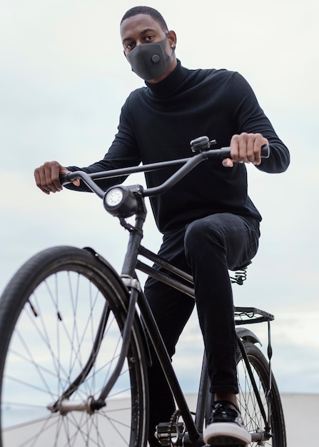 도시에서 그의 자전거를 타고 마스크를 착용하는 남자