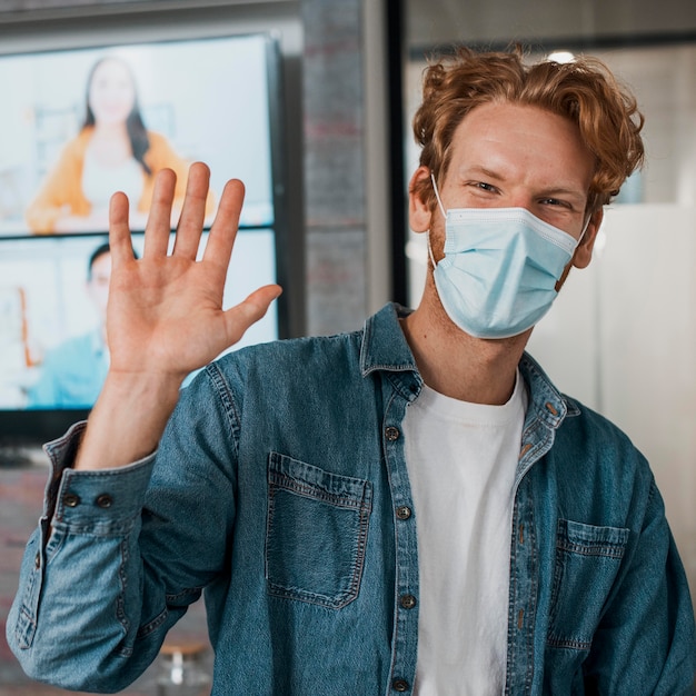 Man wearing medical mask and waving