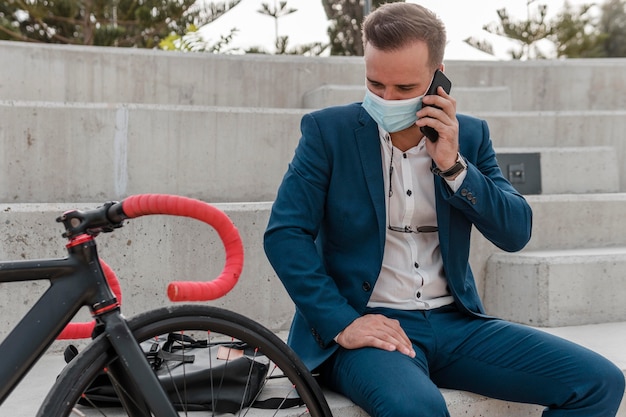 自転車の横に座って医療用マスクを着用している男性