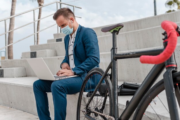 Man wearing a medical mask while sitting next to his bike