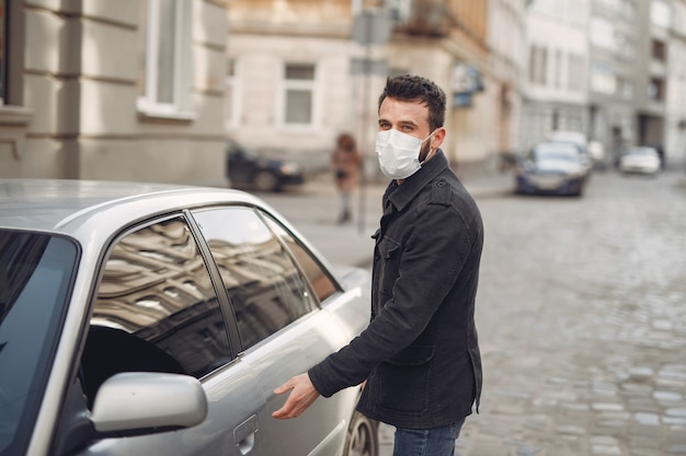 Man wearing a protective mask by a car