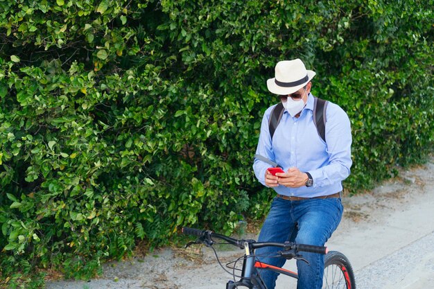 Man wearing protective mask checking cell phone while riding bicycle