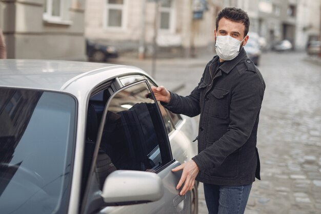 Man wearing a protective mask getting into in a car