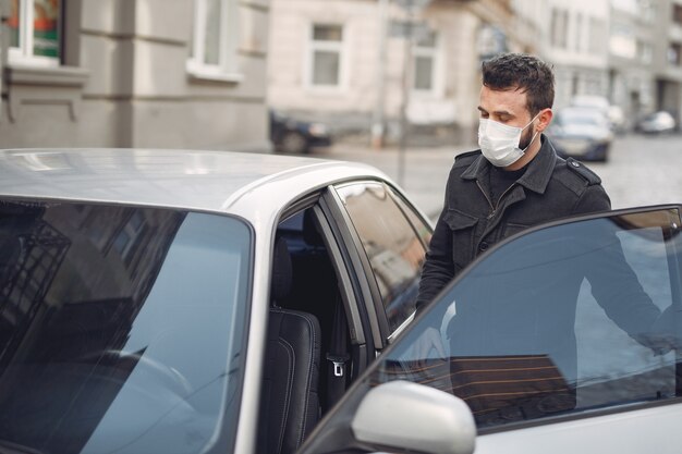 Man wearing a protective mask getting into in a car