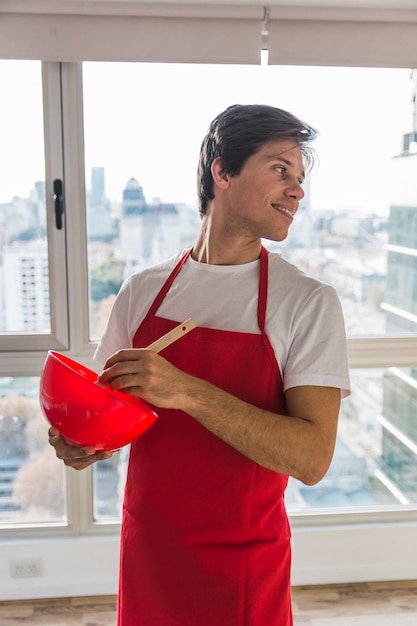 Man wearing red apron cooking food