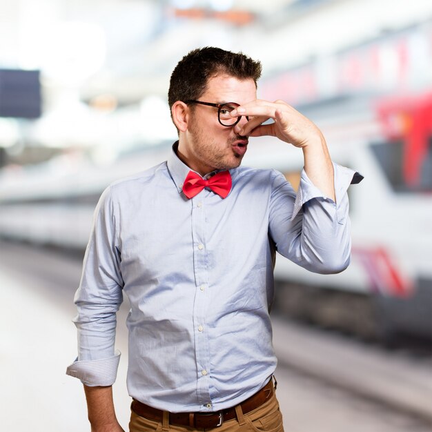 Man wearing a red bow tie. Doing bad smell gesture.