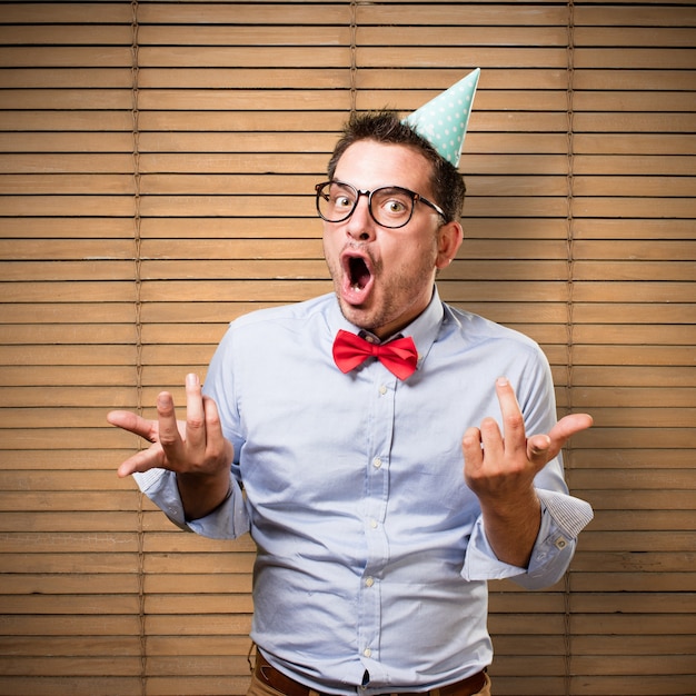 Man wearing a red bow tie and party hat. Looking funny.