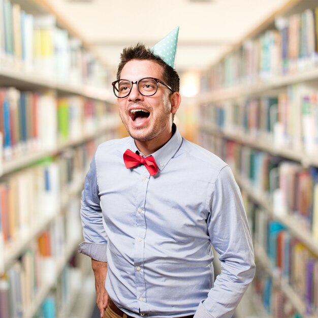 Man wearing a red bow tie and party hat. Looking surprised.