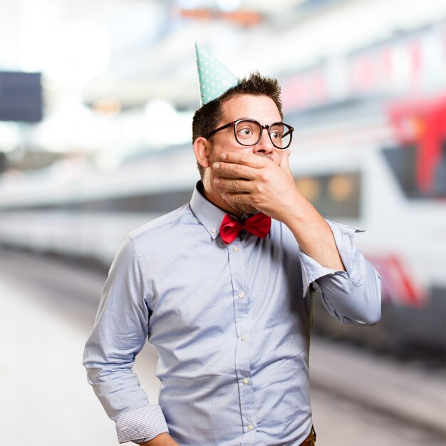 Man wearing a red bow tie and party hat. Looking surprised.