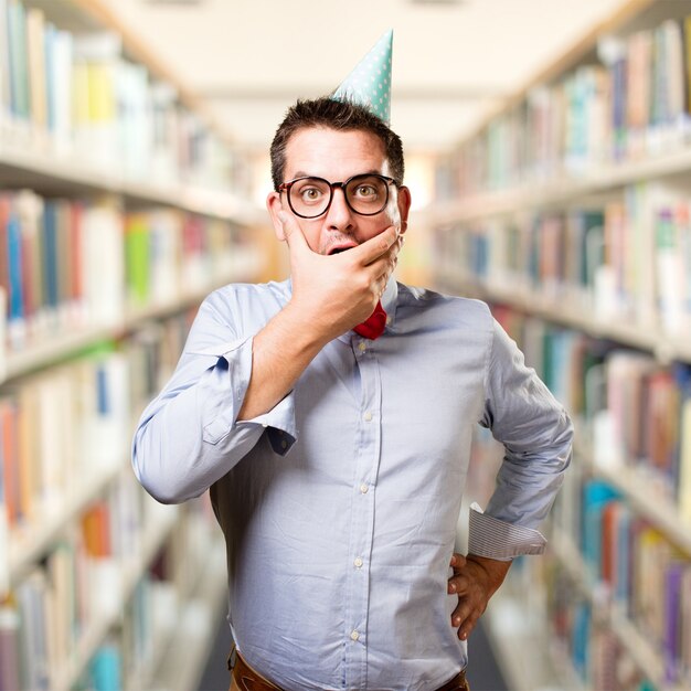 Man wearing a red bow tie and party hat. Looking surprised.