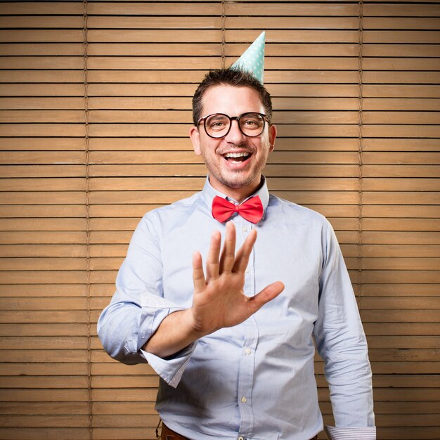Man wearing a red bow tie and party hat. Smiling.