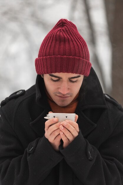 Man wearing red hat looking at a cup of tea