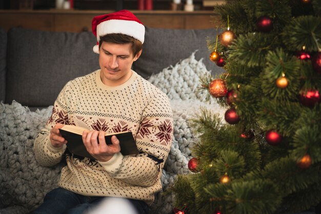 Мужчина в шляпе Санта читает книгу