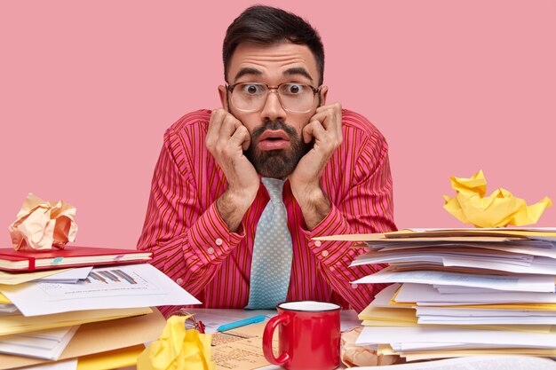 Man wearing shirt and tie sitting at desk with documents