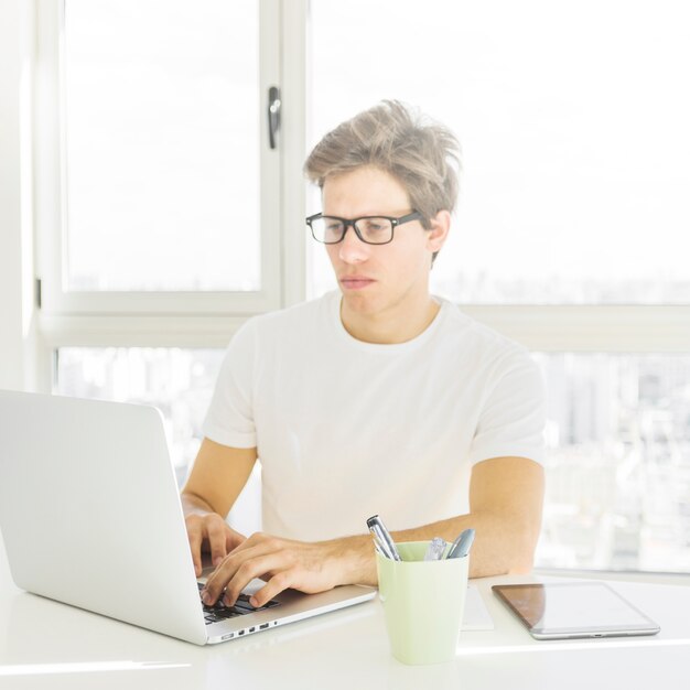 Man wearing spectacles working on laptop at home