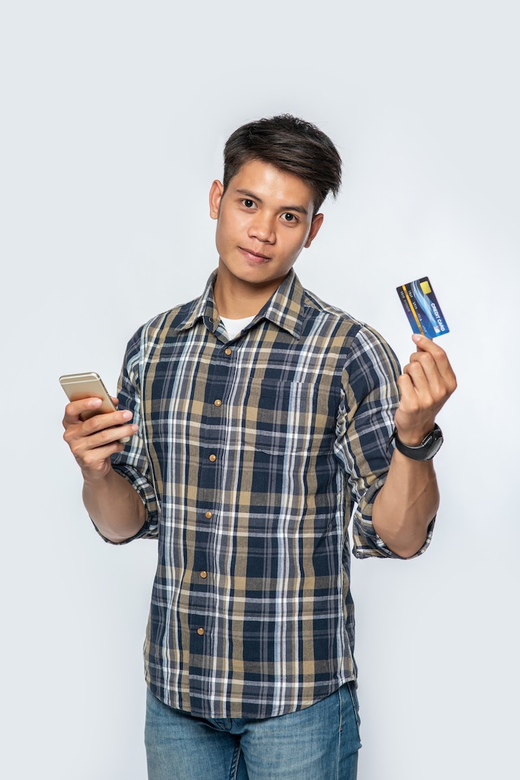 Free Photo a man wearing a striped shirt holds a credit card and smartphone
