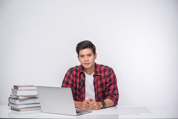 A man wearing a striped shirt uses a laptop to work.