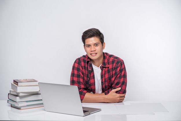 A man wearing a striped shirt uses a laptop to work.