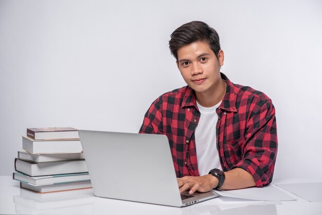 A man wearing a striped shirt uses a laptop to work.