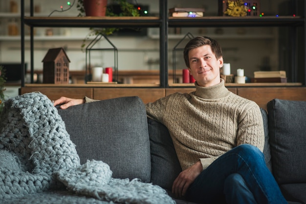 Man wearing sweatter sitting on couch