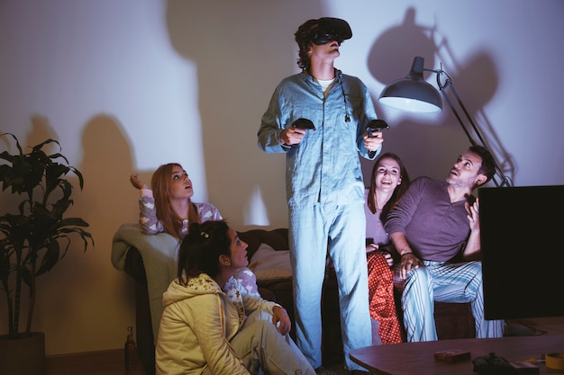 Man wearing vr glasses and friends looking at him