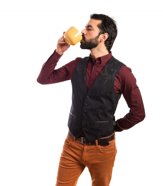 Free photo man wearing waistcoat holding a cup of coffee