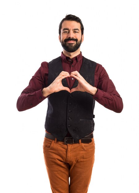 Foto gratuita uomo che indossa il panciotto facendo un cuore con le mani