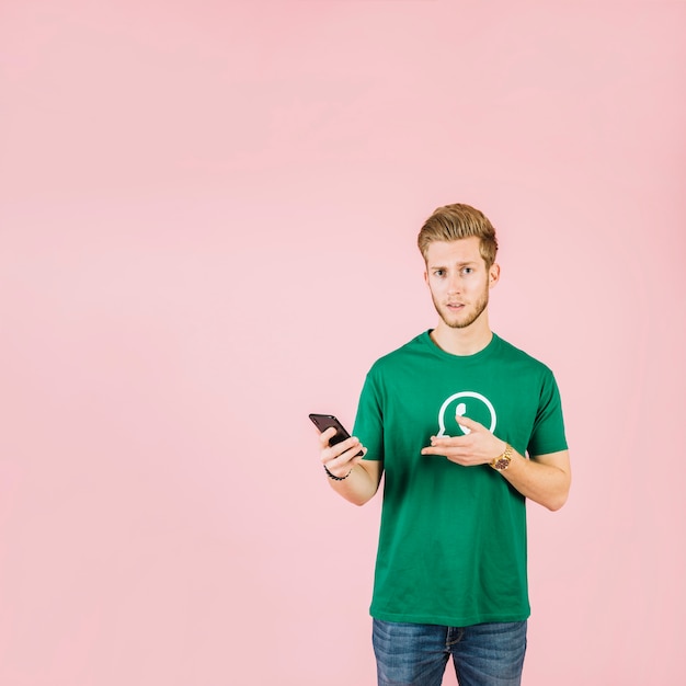 Man wearing whatsapp icon t-shirt gesturing while holding mobile phone