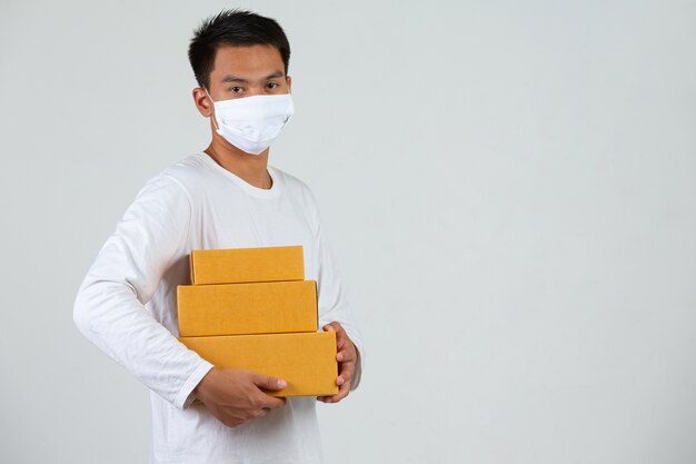 A man wearing a white t-shirt is holding a brown post box to deliver things Make gestures and facial expressions.