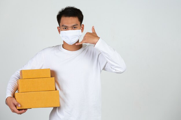 A man wearing a white t-shirt is holding a brown post box to deliver things Make gestures and facial expressions.