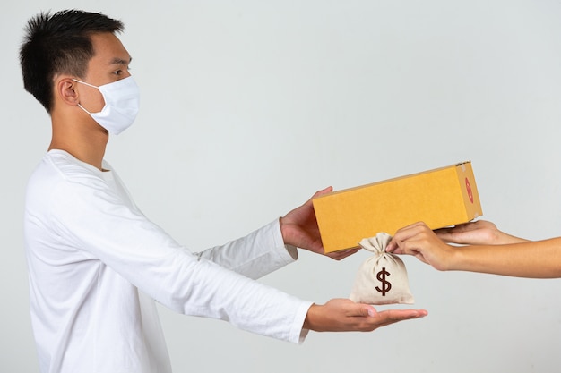 A man wearing a white t-shirt is holding a brown post box to deliver things Make gestures and facial expressions.