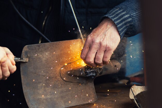 Man welding old shovel, close up.