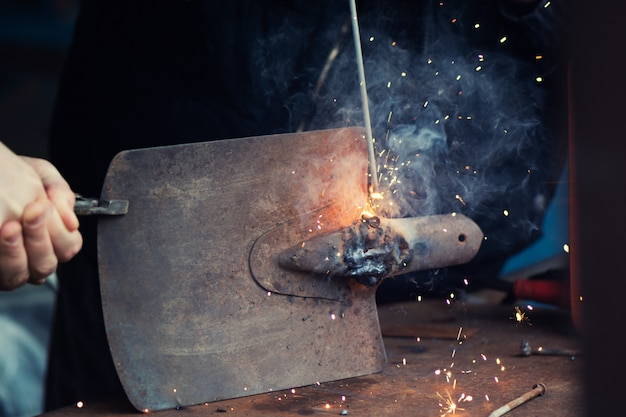 Man welding old shovel, close up.