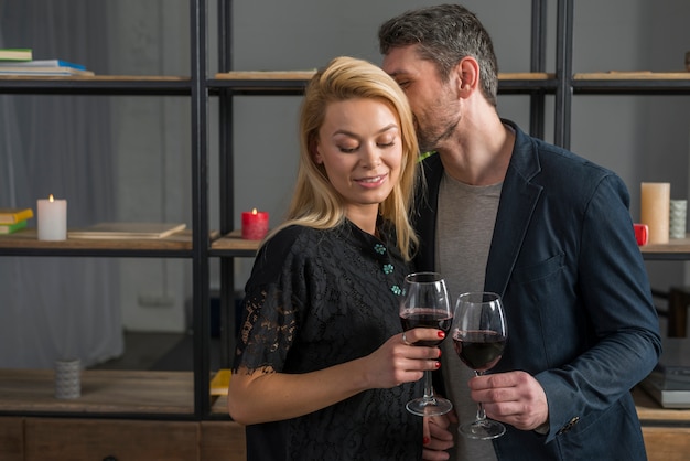 Free photo man whispering to blond woman with glasses of wine