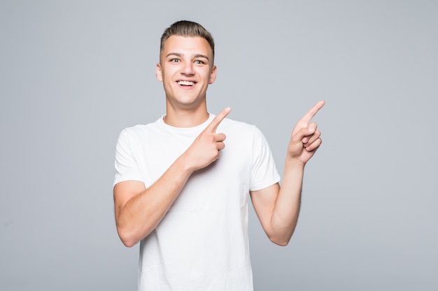 Man in white clothes points on something with both hands fingers isolated on white