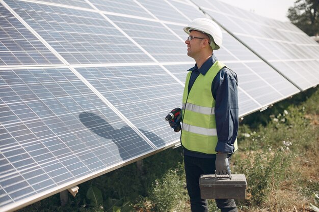 Man in a white helmet near a solar panel