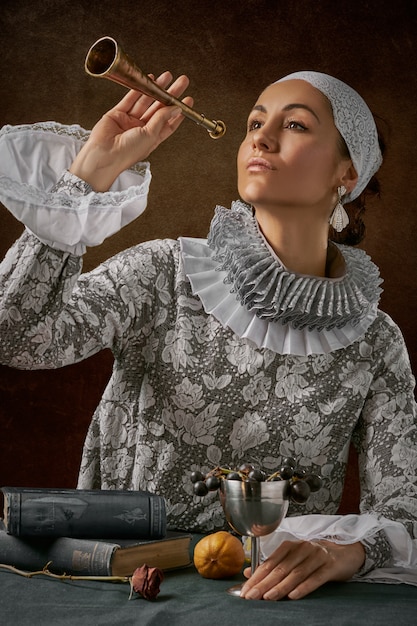 Man in white lace with long sleeved shirt holding trumpet 