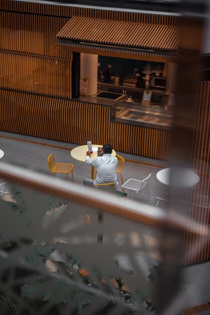 Человек в белой рубашке с длинным рукавом, сидя на стуле в кафе