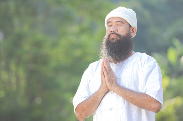 Man in white outfit meditating in nature