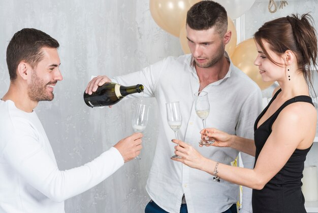 man in white pouring champagne in glasses