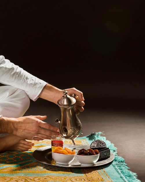 Man in white pouring tea in tiny cup front view