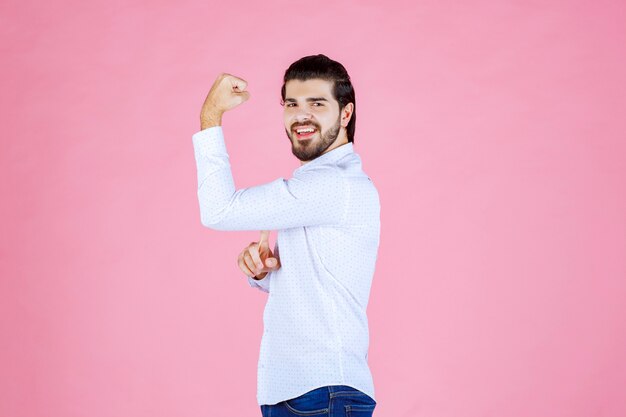 Man in a white shirt demonstrating his arm muscles.