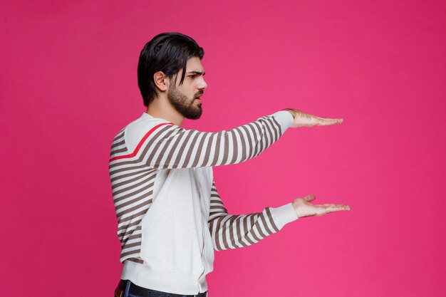 Man in white shirt demonstrating the measures of a parcel. 