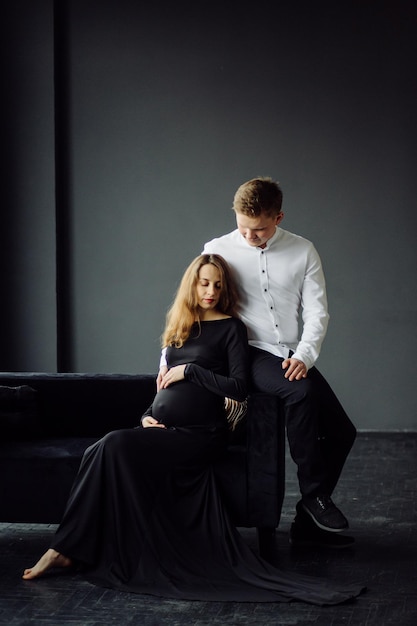 Мужчина в белой рубашке и женщина в черном платье Фото беременности