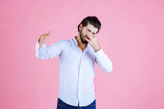 Free photo man in a white shirt holding breath as he feels bad smell.