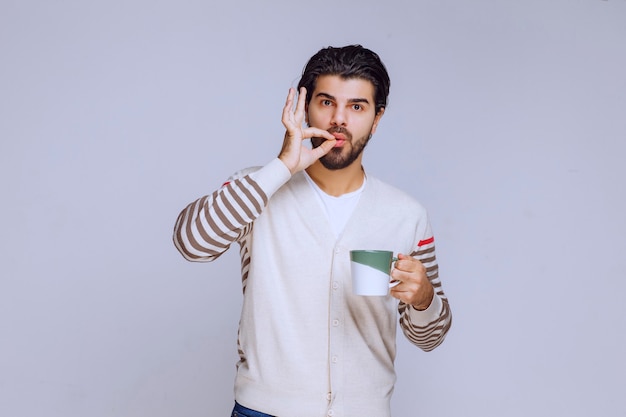 Man in white shirt holding a coffee cup and enjoying it. 