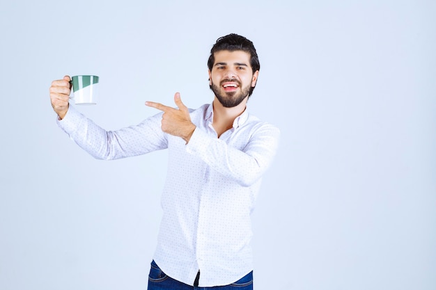 Uomo in camicia bianca che tiene una tazza di caffè e se lo gode