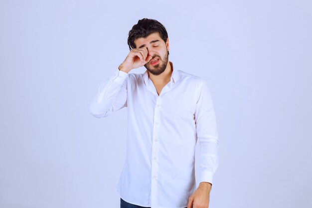 Man in white shirt looks sleepy or sad.